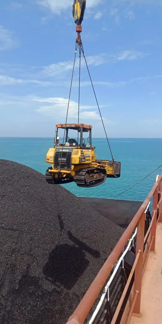 Dozer diangkat crane di atas muatan batu bara dalam palka kapal