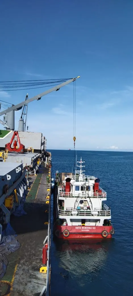 Alat berat diturunkan ke geladak tongkang di laut
