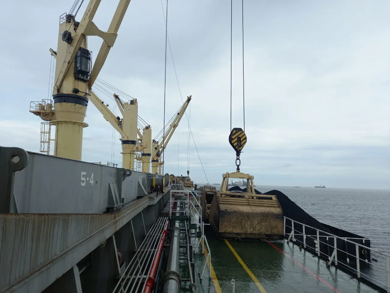 Crane kapal dan grab di geladak kapal gear dengan tongkang batu bara di sisinya